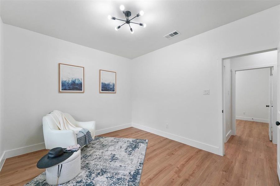 Bright interior space featuring wood-finish flooring, a contemporary ceiling light fixture, white walls, and white baseboards Bright interior space featuring wood-finish flooring, a contemporary ceiling light fixture, white walls, and white baseboards