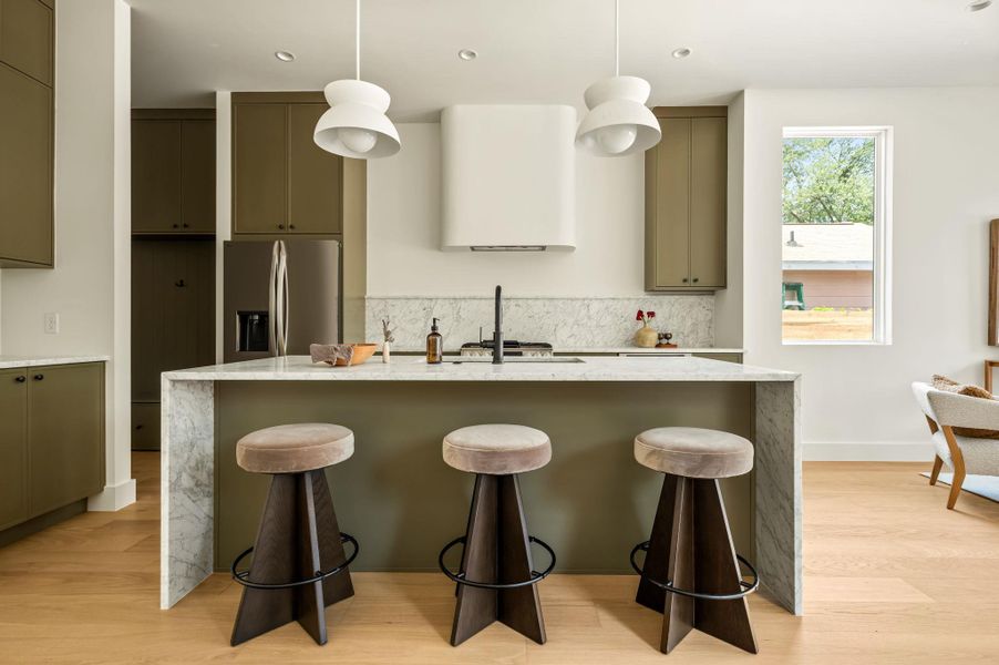Marble waterfall island with bar seating highlights this modern culinary space.