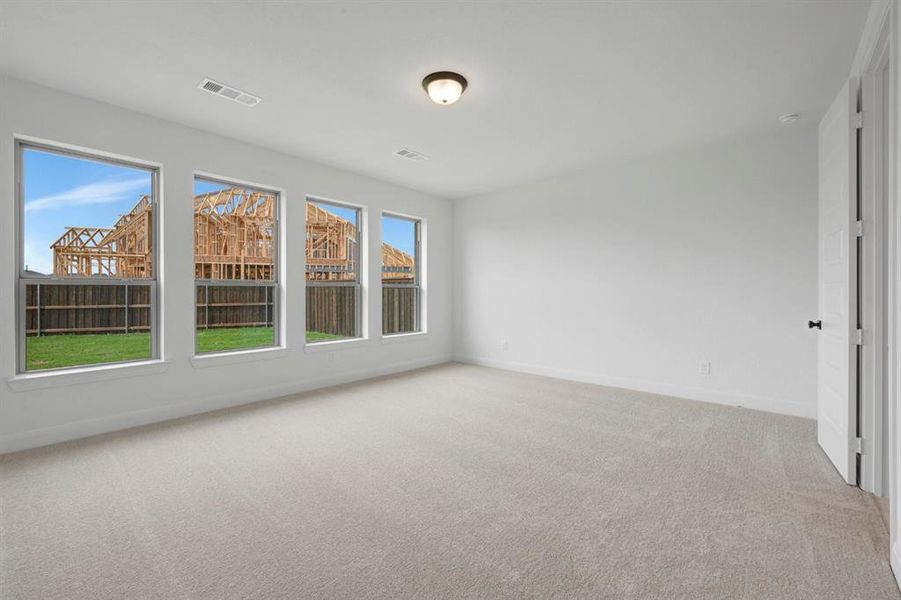 Spacious room featuring four large windows, neutral carpet flooring, white walls, and a flush mount light fixture