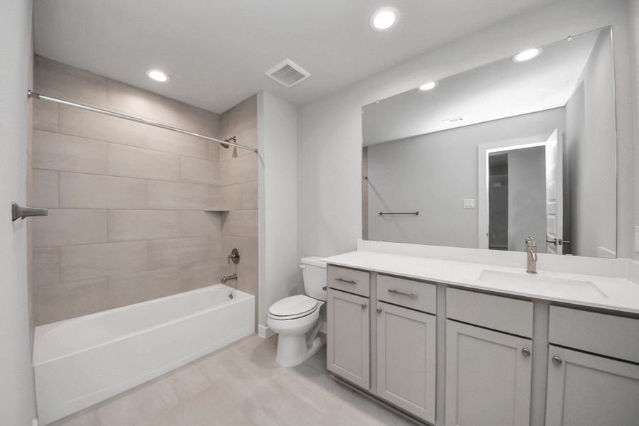 Secondary bath features tile flooring, bath/shower combo with tile surround, light stained wood cabinets, beautiful light countertop. Secondary bath features tile flooring, bath/shower combo with tile surround, light stained wood cabinets, beautiful light countertop.