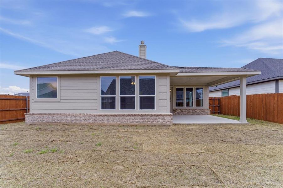 Back of house featuring a fenced backyard, a patio area, a shingled roof, and a chimney
