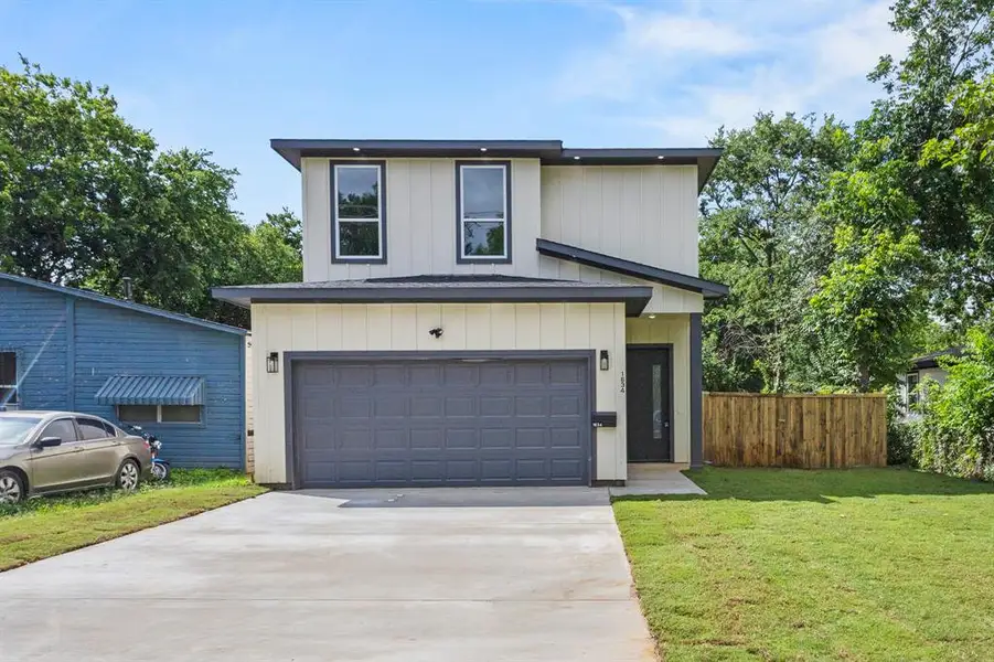 Contemporary two-story residence featuring a neutral exterior with dark trim and a dark garage door Contemporary two-story residence featuring a neutral exterior with dark trim and a dark garage door