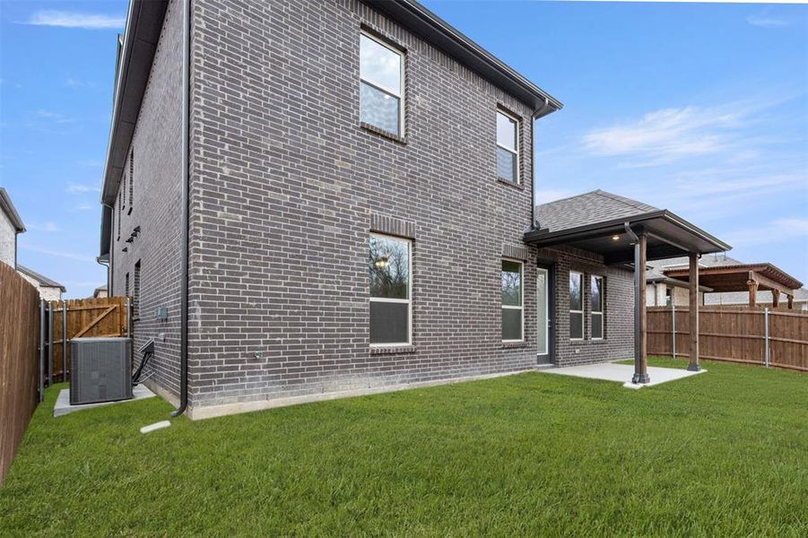 Back of property featuring cooling unit, brick siding, and a patio
