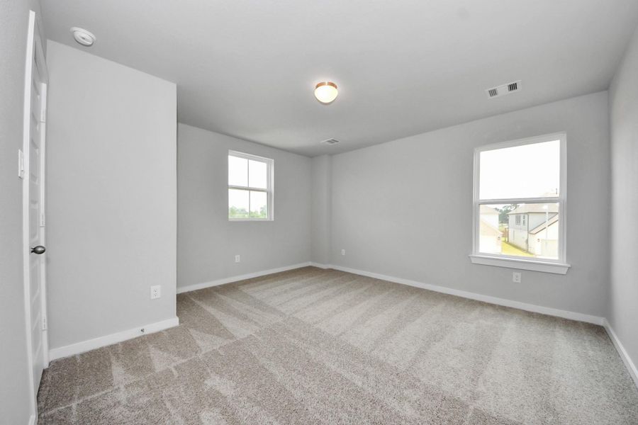 Secondary bedroom features plush carpeting, large windows that let in plenty of natural light, bright paint, and spacious closets. Sample photo of completed home with similar floor plan. Actual colors and selections may vary.