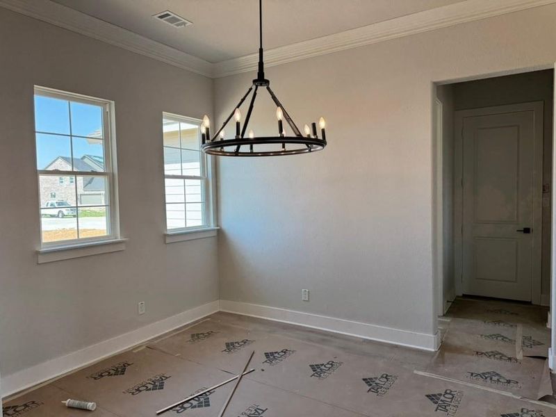 Unfurnished dining area with hanging lights and crown molding