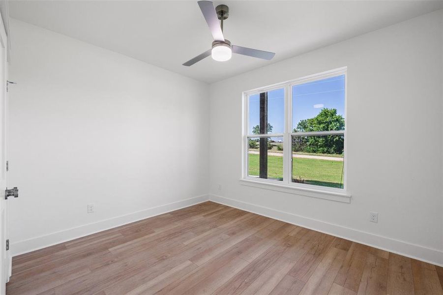 Bright room with wood-finish flooring, white walls, and a modern ceiling fan with integrated lighting