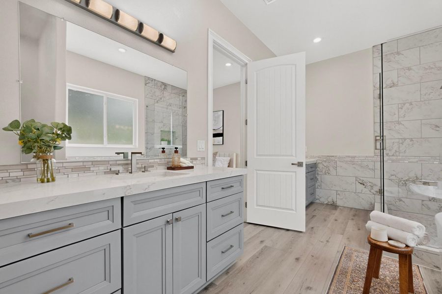Crisp white cabinetry paired with elegant stone-tiled surfaces anchors this refined washroom.