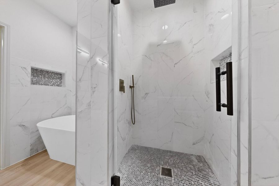 Glass-enclosed shower featuring a rainfall showerhead, handheld shower fixture, and a built-in niche with mosaic tile Glass-enclosed shower featuring a rainfall showerhead, handheld shower fixture, and a built-in niche with mosaic tile