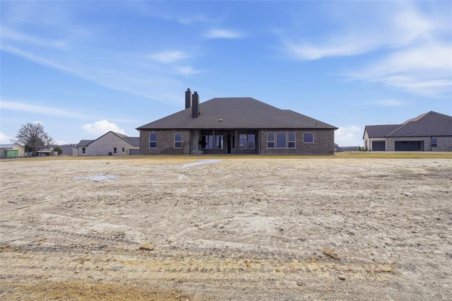 Rear view of house featuring a chimney and brick siding