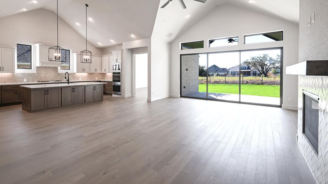 Kitchen with high vaulted ceiling, open floor plan, a ceiling fan, backsplash, and pendant lighting Kitchen with high vaulted ceiling, open floor plan, a ceiling fan, backsplash, and pendant lighting