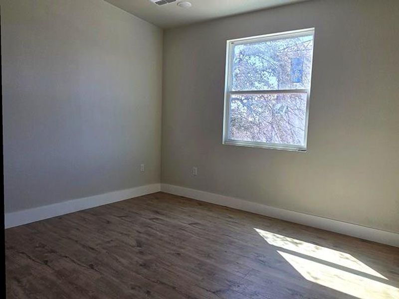 Empty room featuring dark wood-style flooring and baseboards