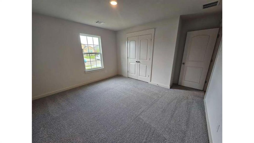 Spacious room featuring neutral carpeting, a double-paned window, and white interior doors