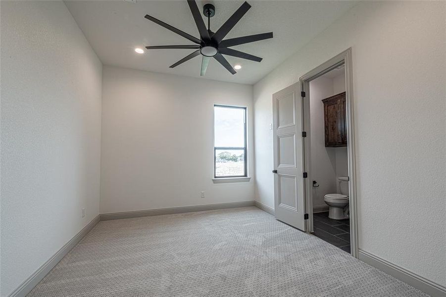 Unfurnished bedroom with a ceiling fan, connected bathroom, carpet, a textured wall, and recessed lighting Unfurnished bedroom with a ceiling fan, connected bathroom, carpet, a textured wall, and recessed lighting