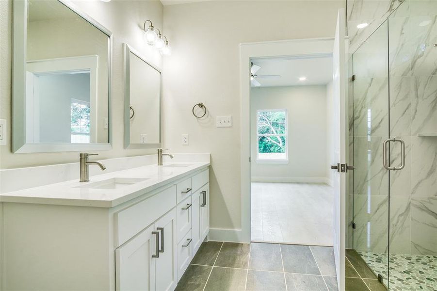 Bathroom with ceiling fan, a marble finish shower, a sink, and tile patterned floors