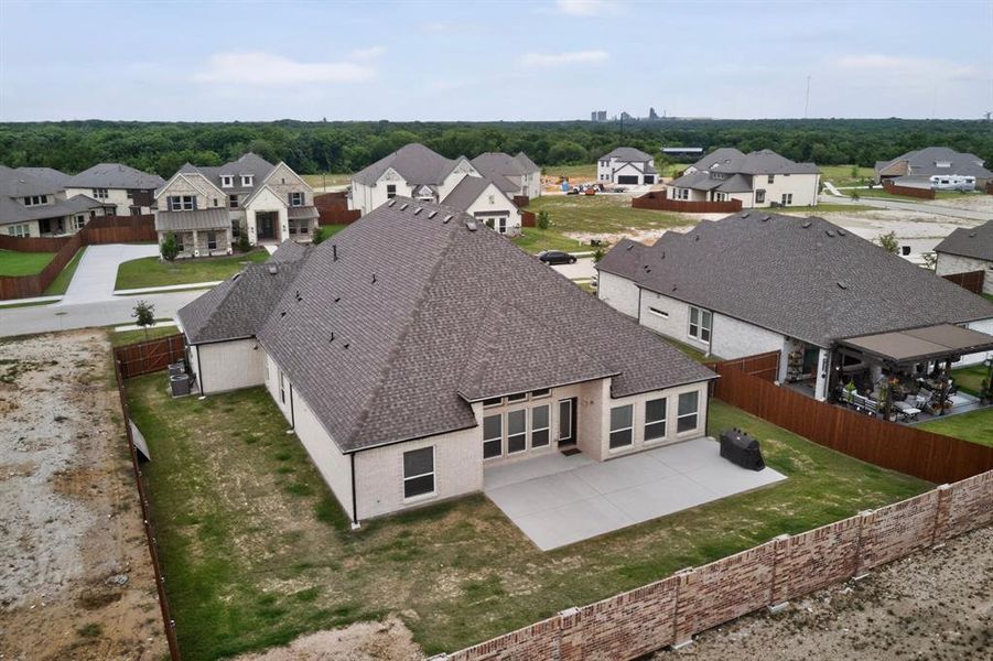 Rear exterior featuring a spacious concrete patio, multiple large windows, and a mature treeline in the distance Rear exterior featuring a spacious concrete patio, multiple large windows, and a mature treeline in the distance