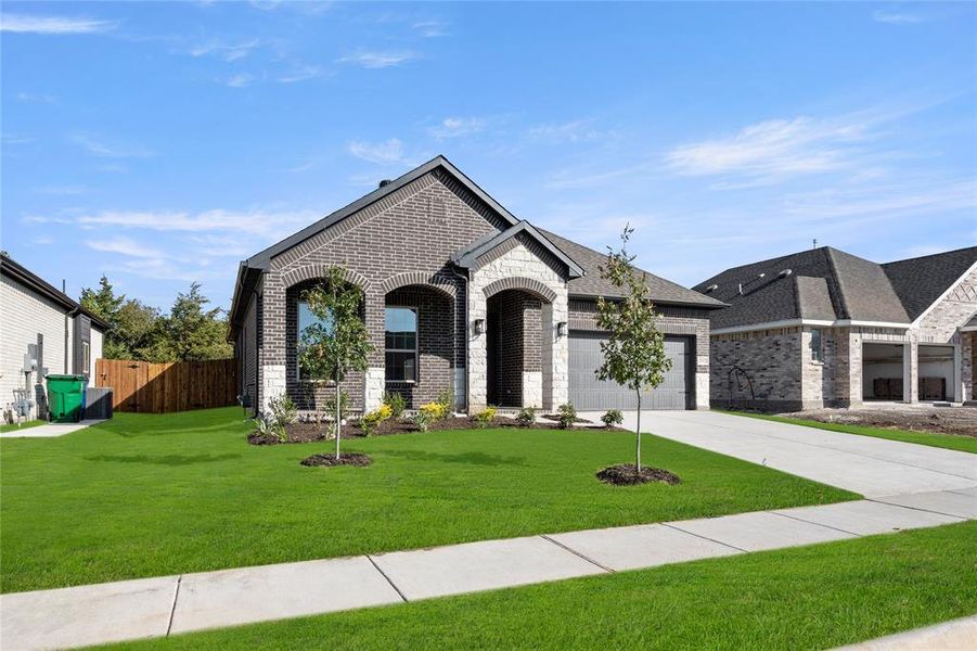 French provincial home featuring brick siding, concrete driveway, and an attached garage
