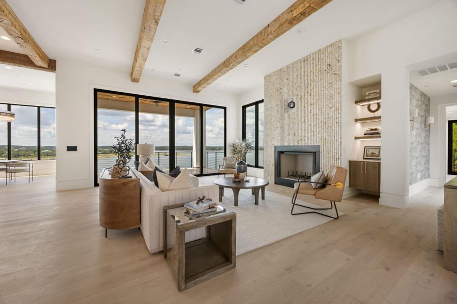 Exposed wood beams crown this elegant living area, featuring a cozy fireplace and expansive glass doors opening to captivating water views. Exposed wood beams crown this elegant living area, featuring a cozy fireplace and expansive glass doors opening to captivating water views.