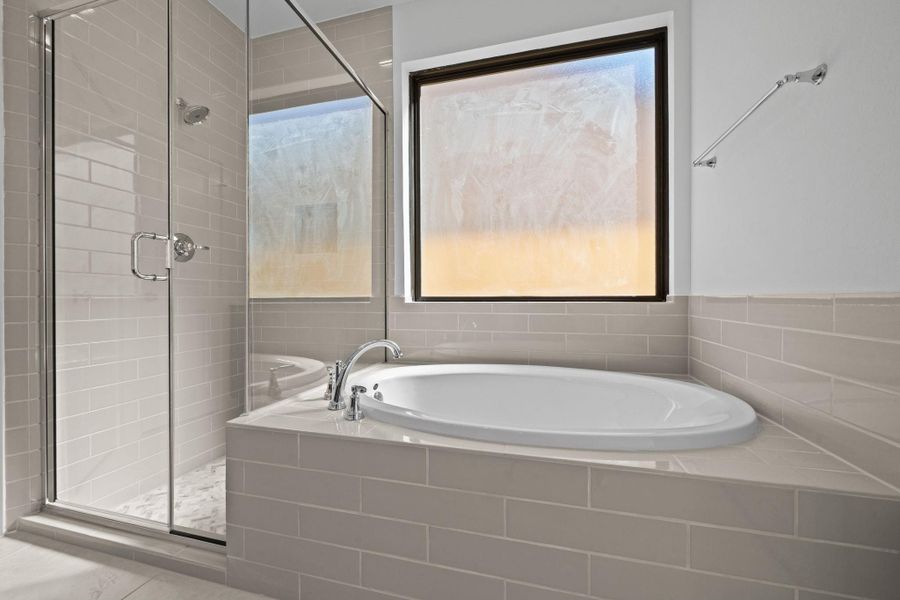 This bathroom features a luxurious soaking tub, perfect for relaxing in deep, warm water, paired with a sleek stand-up shower that offers a modern, convenient alternative. Together, they create a versatile and spa-like retreat, combining comfort, style, and functionality in one elegant space.
