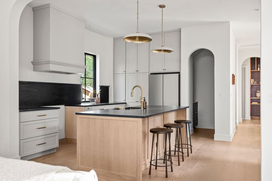 An inviting kitchen features a central island, recessed lighting, and a charming hallway with built-in shelves.