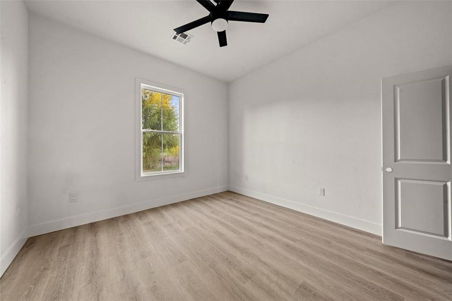 Unfurnished room with light wood-type flooring, lofted ceiling, and a ceiling fan Unfurnished room with light wood-type flooring, lofted ceiling, and a ceiling fan