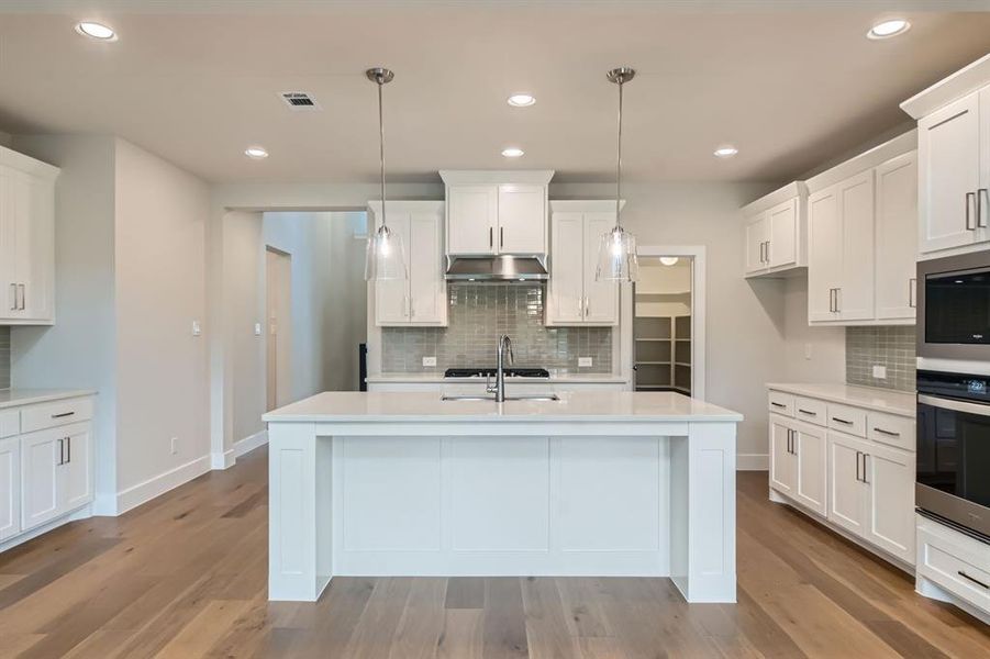 Kitchen with stainless steel appliances, under cabinet range hood, light countertops, decorative backsplash, and recessed lighting Kitchen with stainless steel appliances, under cabinet range hood, light countertops, decorative backsplash, and recessed lighting