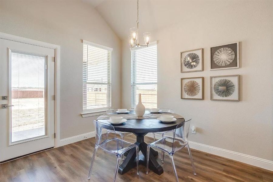 Dining room with an inviting chandelier, hardwood / wood-style flooring, and vaulted ceiling