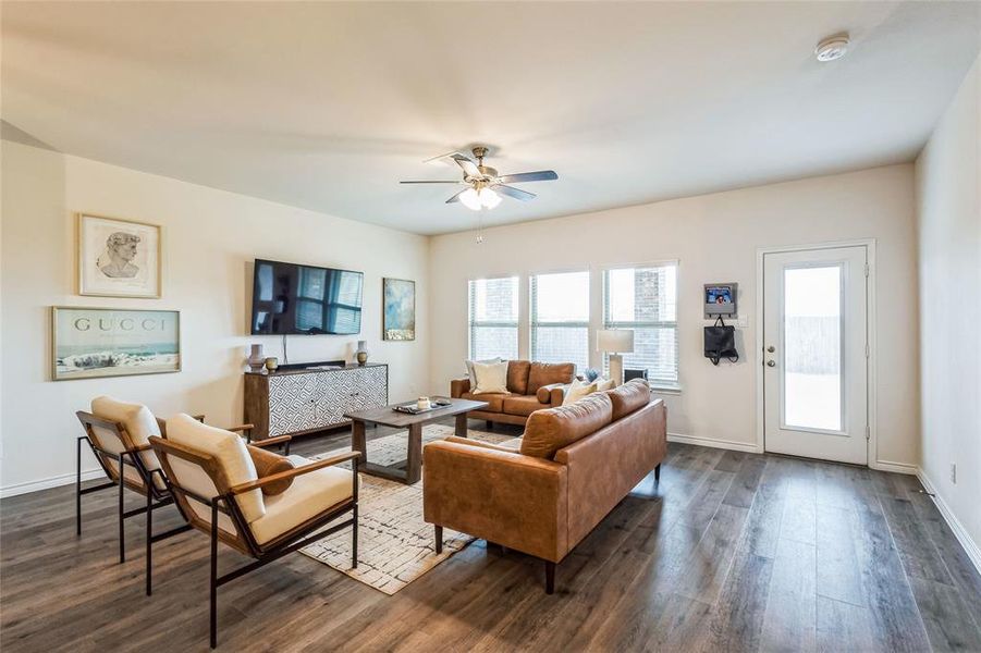 Living area featuring dark wood-style flooring, ceiling fan, and baseboards