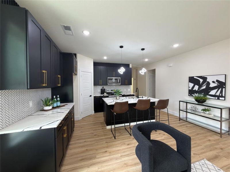 Contemporary kitchen with dark cabinetry, gold-finish hardware, and a herringbone tile backsplash