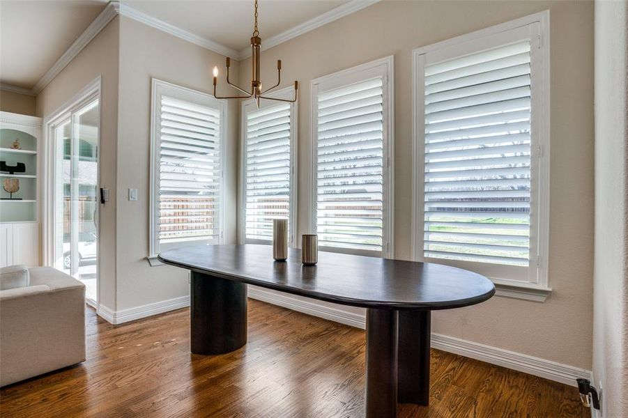 Dining space featuring ornamental molding, dark wood-type flooring, and a notable chandelier