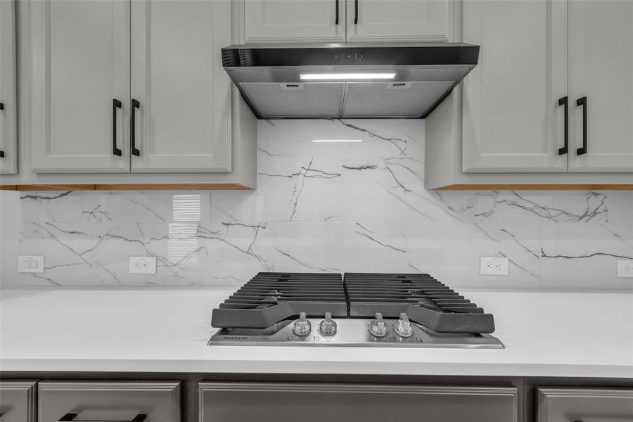 Gas cooktop complemented by a full tile backsplash.