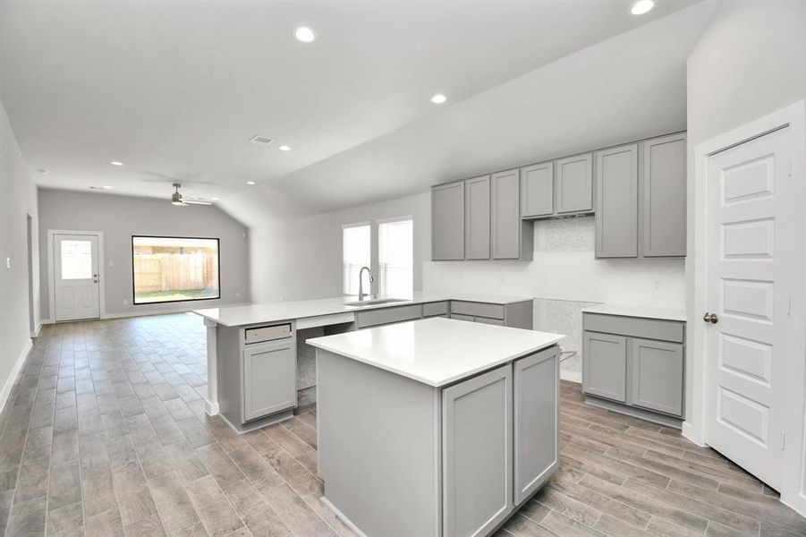 This generously spacious culinary haven features a massive granite island, high ceilings, soft-close cabinets, granite countertops, stainless steel appliances (to be installed), a sleek tile backsplash, and recessed lighting. Sample photo of completed home with similar floor plan. Actual colors and selections may vary.