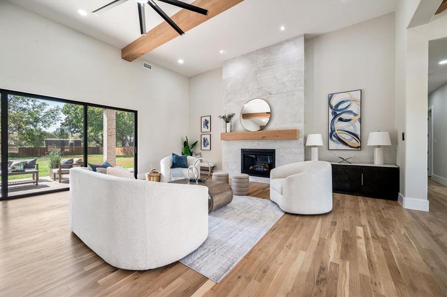 Living room featuring light hardwood / wood-style flooring, ceiling fan, high vaulted ceiling, and a fireplace