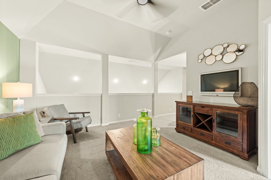 Living room with vaulted ceiling, ceiling fan, gray sofa, wood coffee table, and TV on a wood media console