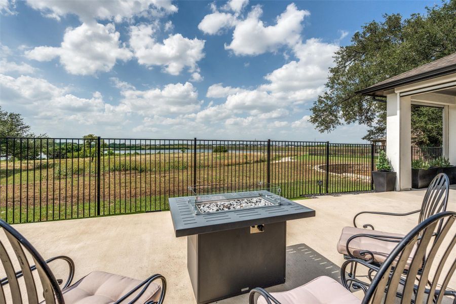 Concrete patio spaces overlook a grassy lawn bordered by metal fencing.