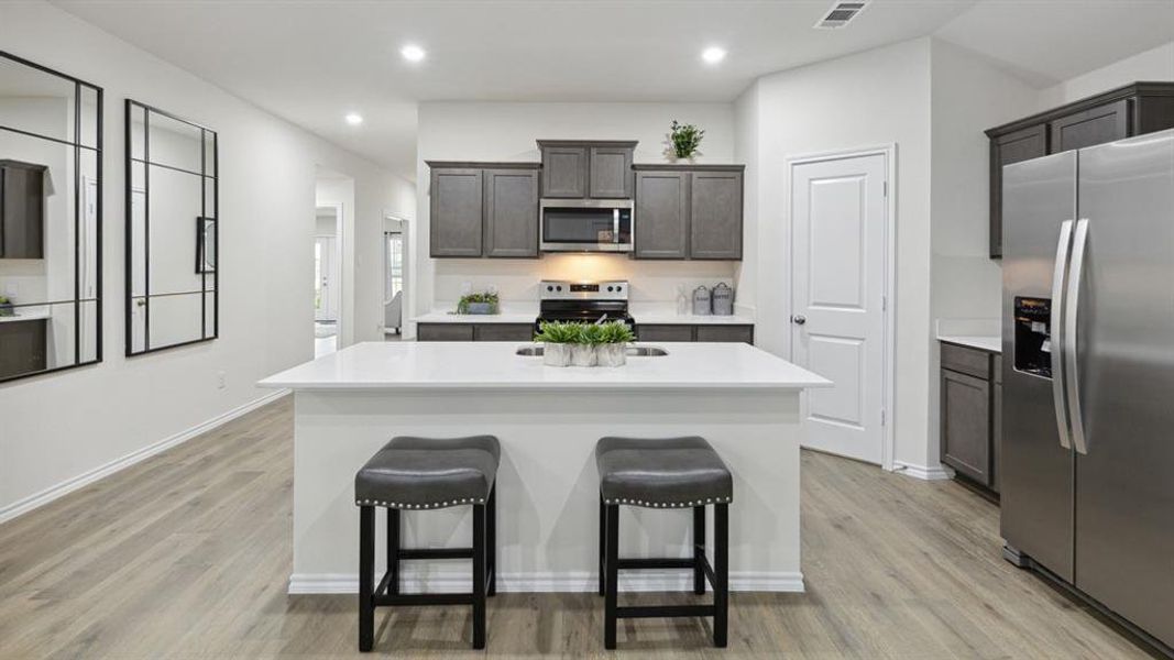 Kitchen with stainless steel appliances, an island with sink, recessed lighting, and light wood-style floors Kitchen with stainless steel appliances, an island with sink, recessed lighting, and light wood-style floors
