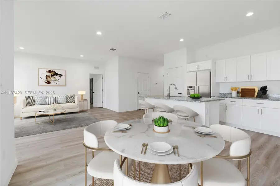 Open-concept living space featuring wood-finish flooring, recessed lighting, white cabinetry, a kitchen island with stone-finish countertops, and stainless-steel appliances Open-concept living space featuring wood-finish flooring, recessed lighting, white cabinetry, a kitchen island with stone-finish countertops, and stainless-steel appliances