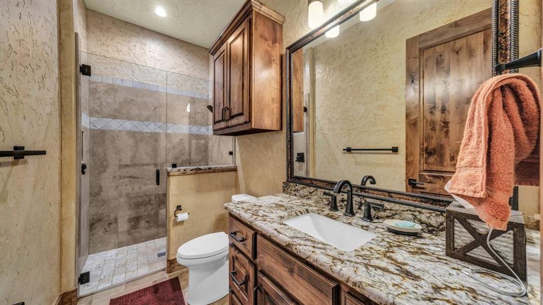 Stylish bath with granite vanity, framed mirror, and a walk-in shower with glass enclosure.