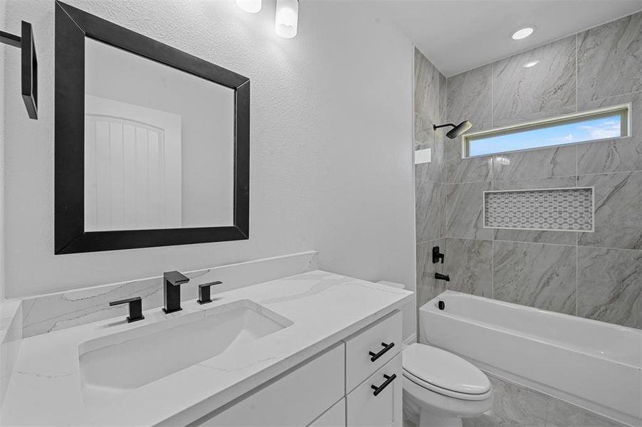 Full bathroom with vanity, toilet, tile patterned floors, and tiled shower / bath