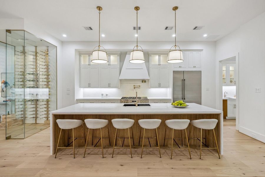 This stunning chef's kitchen showcases a dramatic Quartz waterfall island with ample seating, perfect for entertaining. Crisp white inset cabinetry and glass front upper cabinets maintain visual lightness, while Wood accents and Aged Gold pendant lighting introduce depth and structure. Stainless Appliances, custom hood, Pot Filler, under-cabinet lighting, warm wood floors, and abundant natural light complete this elegant, modern space. This stunning chef's kitchen showcases a dramatic Quartz waterfall island with ample seating, perfect for entertaining. Crisp white inset cabinetry and glass front upper cabinets maintain visual lightness, while Wood accents and Aged Gold pendant lighting introduce depth and structure. Stainless Appliances, custom hood, Pot Filler, under-cabinet lighting, warm wood floors, and abundant natural light complete this elegant, modern space.