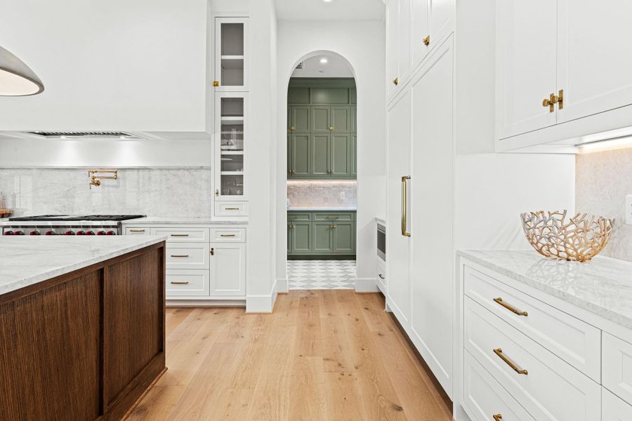 Glass-front display shelving flanks the range, while a pot filler & thoughtful storage details enhance both form & function. Pull-out utensil & spice rack drawers add everyday convenience. Sonos speakers installed. An arched walkway leads to the convenient scullery kitchen, creating a seamless extension of the space. Glass-front display shelving flanks the range, while a pot filler & thoughtful storage details enhance both form & function. Pull-out utensil & spice rack drawers add everyday convenience. Sonos speakers installed. An arched walkway leads to the convenient scullery kitchen, creating a seamless extension of the space.