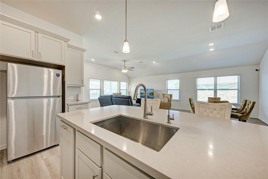 A contemporary kitchen features an open-concept layout with ample countertop space, connecting seamlessly to a sun-filled living area.