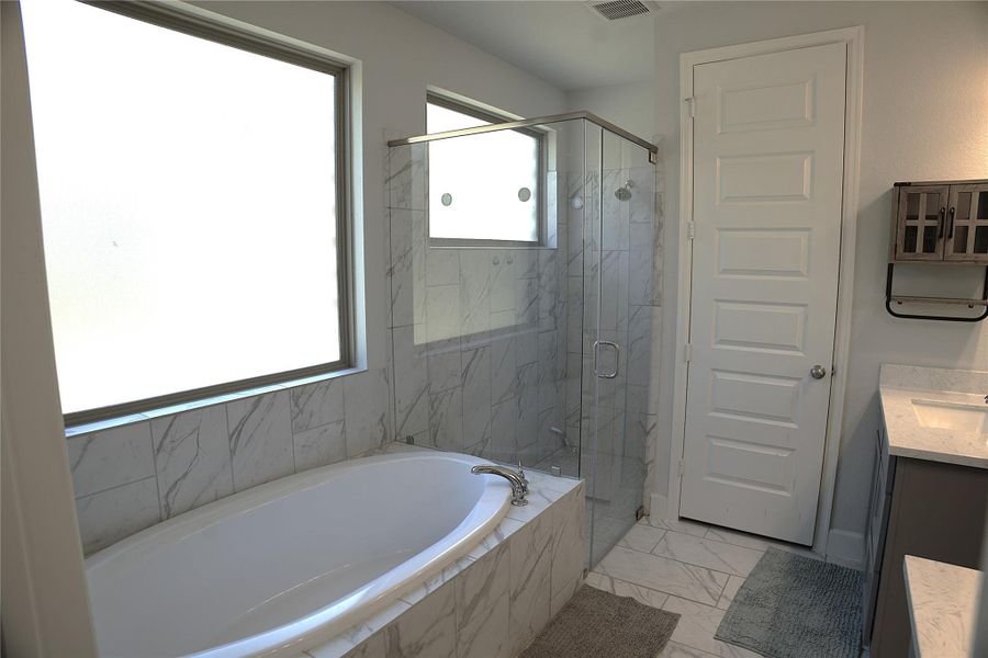 Full bathroom featuring vanity, light marble finish flooring, a marble finish shower, and a bath Full bathroom featuring vanity, light marble finish flooring, a marble finish shower, and a bath