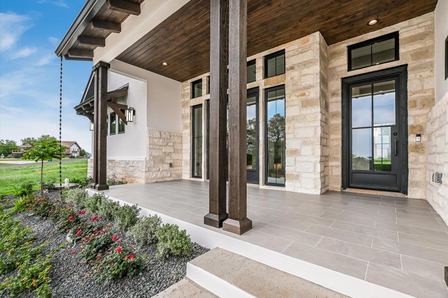Expansive front porch featuring stone and stucco exterior, wood-finish ceiling, dark wood columns, and grid-patterned glass entry doors