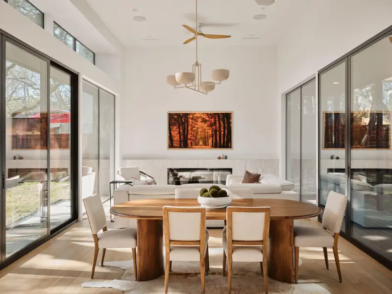 Dining area with wood finished floors, a high ceiling, a ceiling fan, and a wainscoted wall