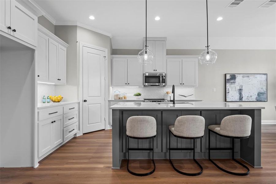 Kitchen featuring white cabinetry, decorative backsplash, dark wood finished floors, a kitchen bar, and recessed lighting Kitchen featuring white cabinetry, decorative backsplash, dark wood finished floors, a kitchen bar, and recessed lighting