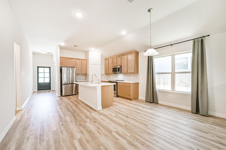 An alternate view of the kitchen highlights its openness to the main living areas, including the breakfast nook, which is beautifully complemented by a stylish pendant light. An alternate view of the kitchen highlights its openness to the main living areas, including the breakfast nook, which is beautifully complemented by a stylish pendant light.