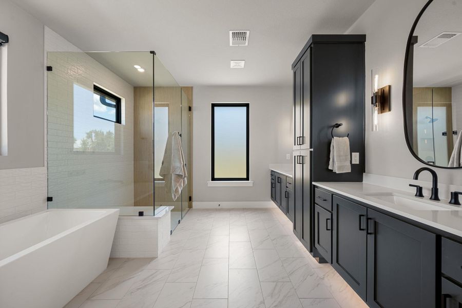Modern finishes define this master bath featuring a freestanding tub and sleek glass shower.