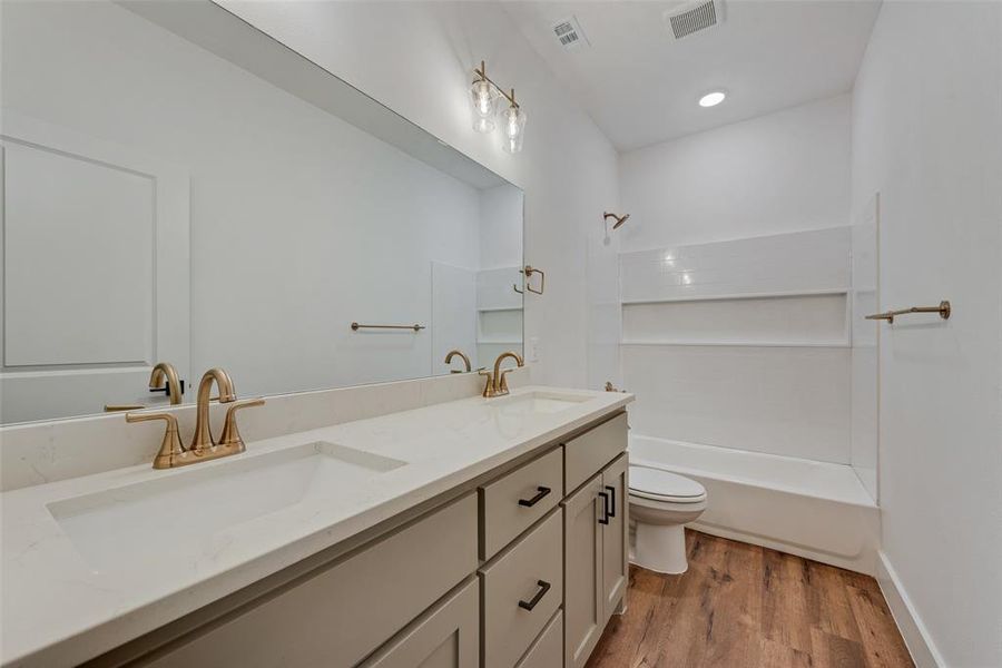 Full bath featuring shower / tub combination, double vanity, and light wood-style flooring Full bath featuring shower / tub combination, double vanity, and light wood-style flooring