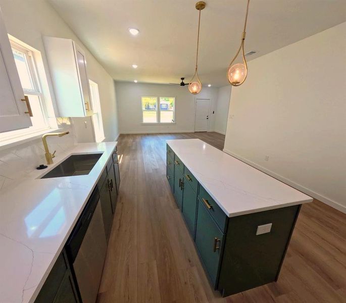 Kitchen with light wood finished floors, a center island, hanging light fixtures, open floor plan, and dishwasher Kitchen with light wood finished floors, a center island, hanging light fixtures, open floor plan, and dishwasher