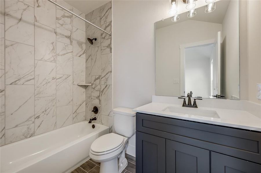 The secondary bathroom is just as beautiful as the primary bathroom- dark wood cabinets and handsome tilework.